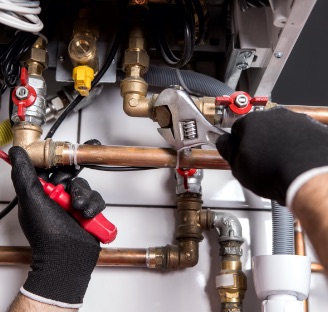 persons hands in black gloves fixing heater with wrench